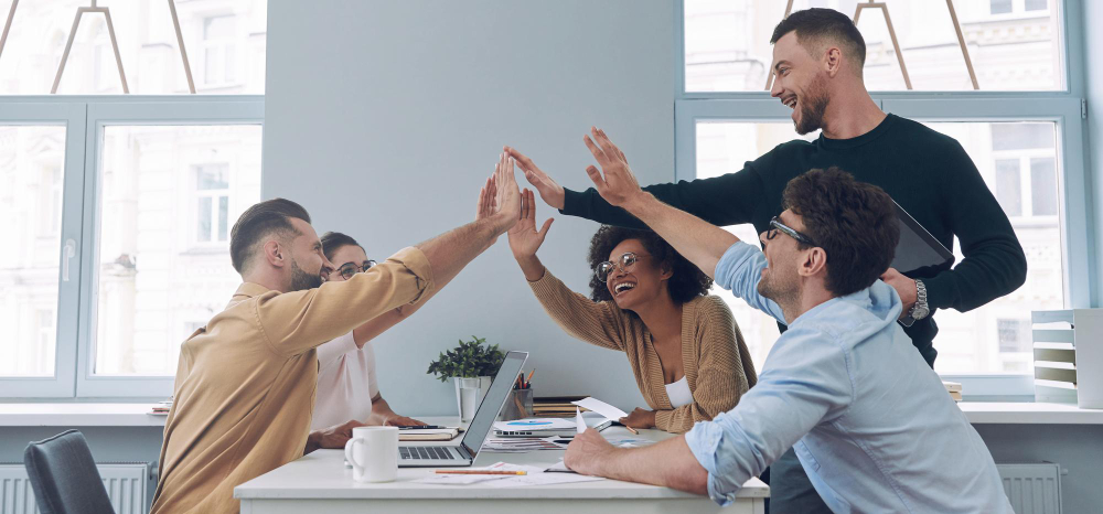 Empleados aplaudiendo durante una presentación, reflejando un ambiente laboral positivo.