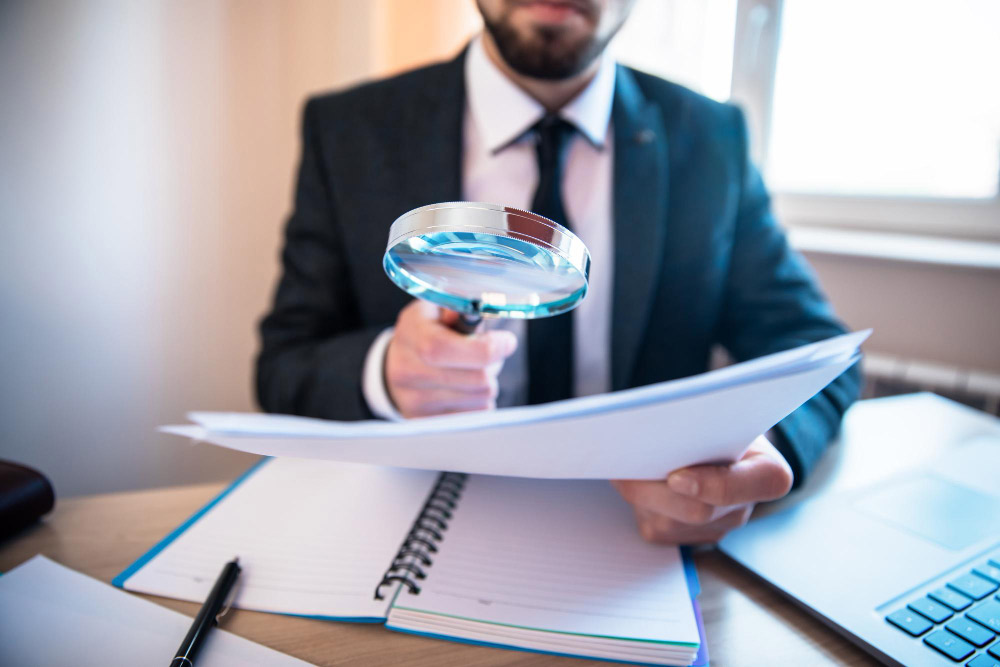 Hombre con lupa, revisando los beneficios de la evaluación de riesgos psicosociales