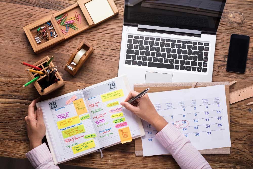 Agenda con notas y calendario junto a un portátil, representando planificación y seguimiento del trabajo autónomo.