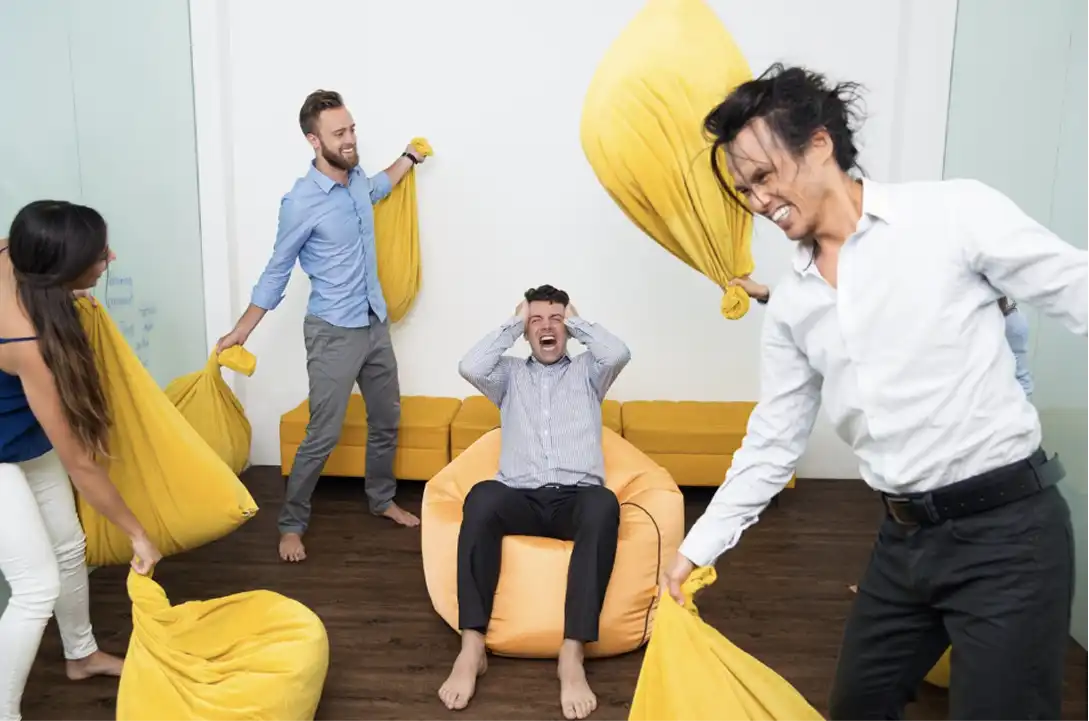 Equipo de trabajando un en conflicto con cojines en una empresa con cultura organizacional conflictiva Equipo de trabajando un en conflicto con cojines en una empresa con cultura organizacional conflictiva