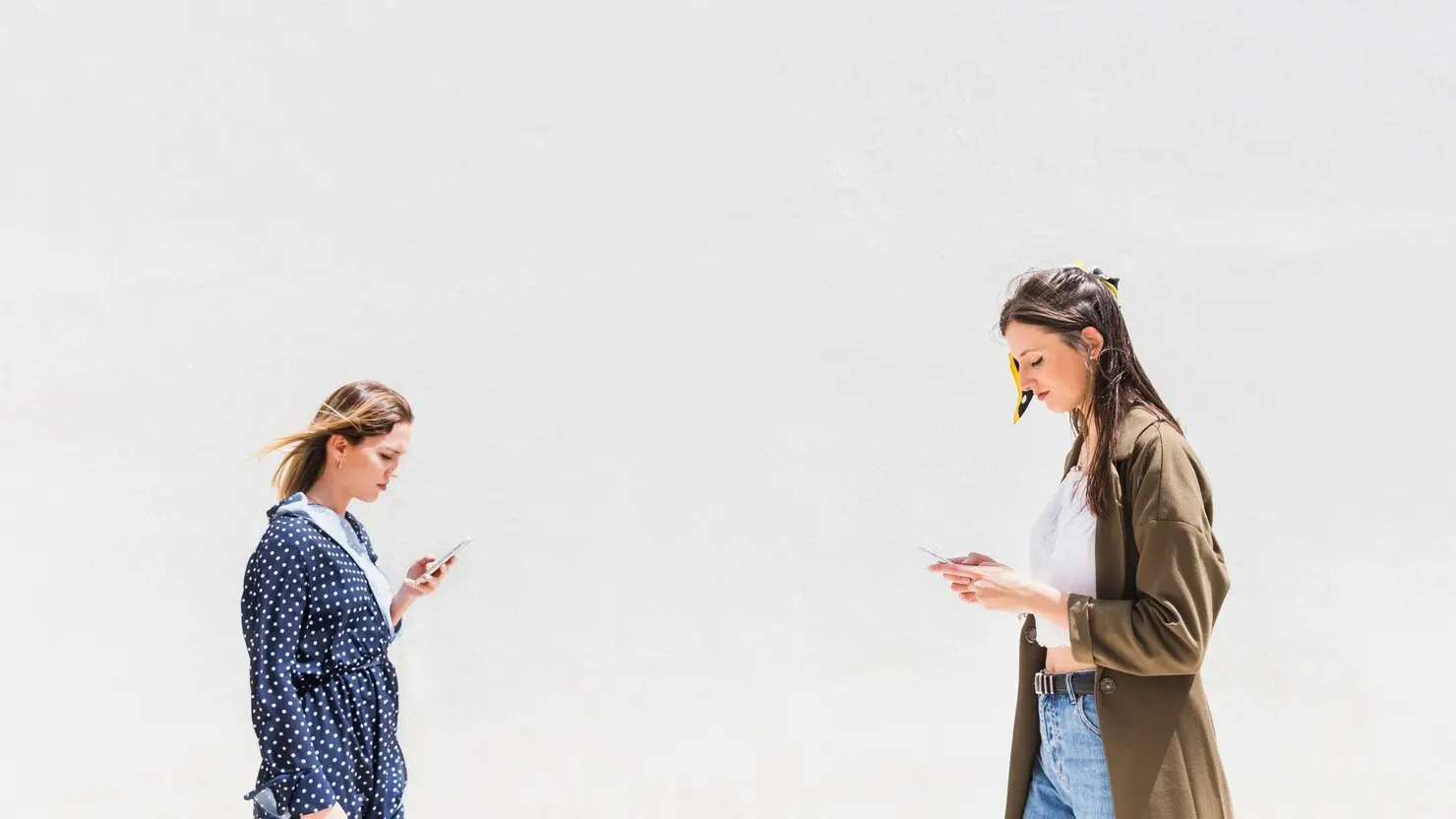 Dos mujeres hablando por celular una al frente de la otra